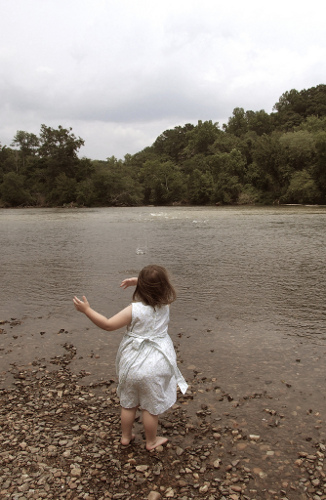 Girl throwing rock into river