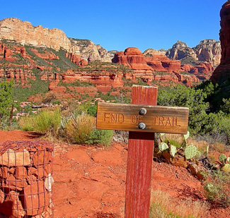 Weathered "end of trail" sign in front of a rocky desert terrain