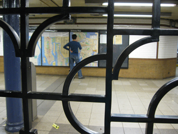 Man reading a NYC subway map, through a gate, photo by Alyce Wilson